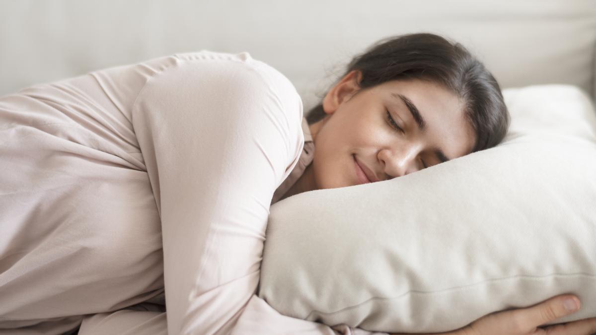 Mujer duerme abrazada a la almohada.