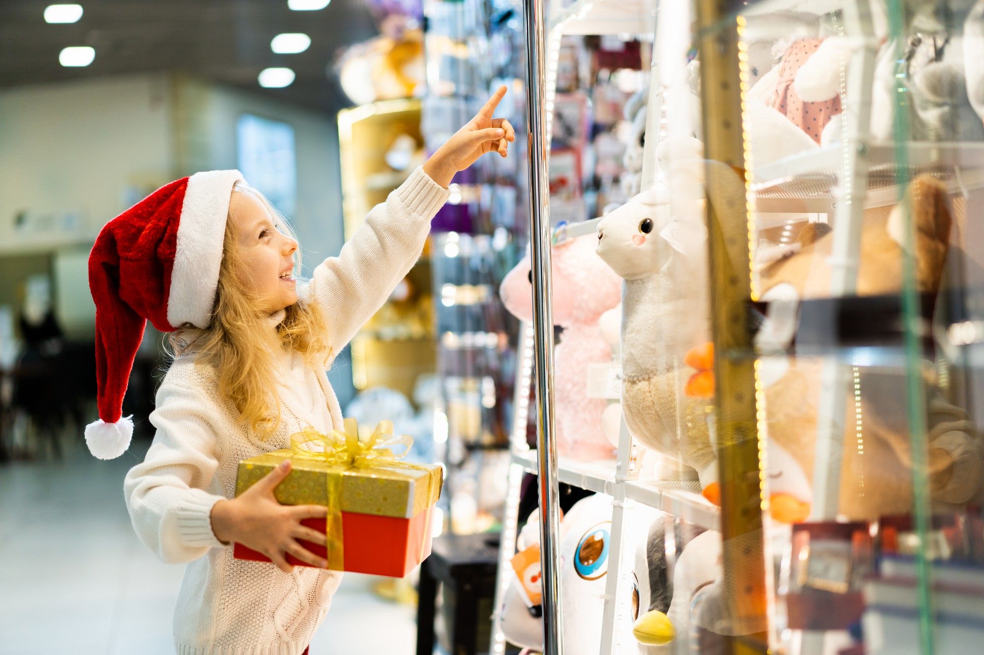 Una niña sonríe mientras señala su peluche favorito.