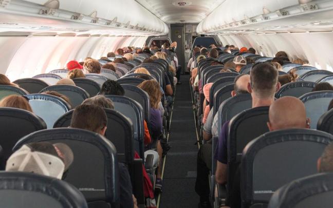 Los pasajeros de un avión ocupan sus asientos.