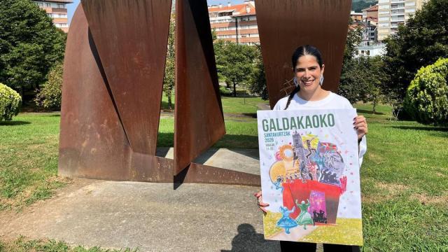 La ganadora del concurso, Ane Kareaga Graña, muestra el cartel junto a la escultura de Oteiza