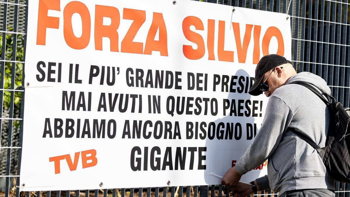 Un simpatizante cuelga una pancarta en apoyo a Berlusconi en el hospital de San Raffaele.