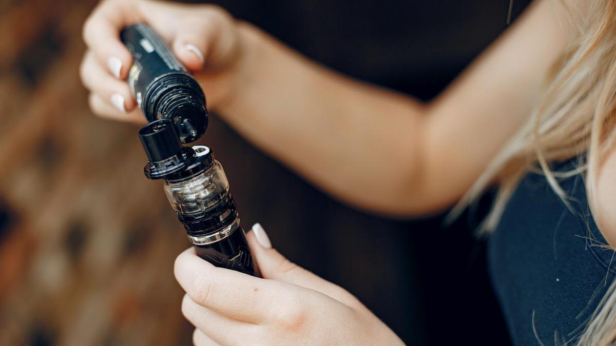Una joven recarga un dispositivo vapeador.