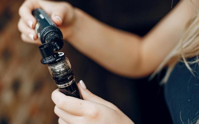 Una joven recarga un dispositivo vapeador. / Freepik Una joven recarga un dispositivo vapeador.