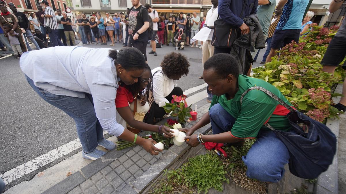 Allegados de Babacar Welle encienden velas junto a las flores colocadas en el lugar en el que murió el senegalés por disparos de la policía.