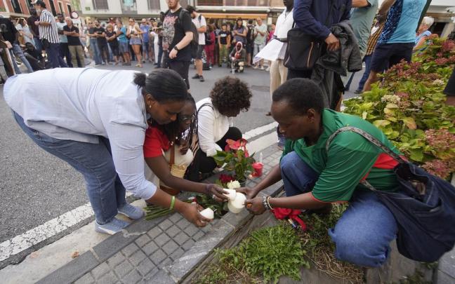 Allegados de Babacar Welle encienden velas junto a las flores colocadas en el lugar en el que murió el senegalés por disparos de la policía.