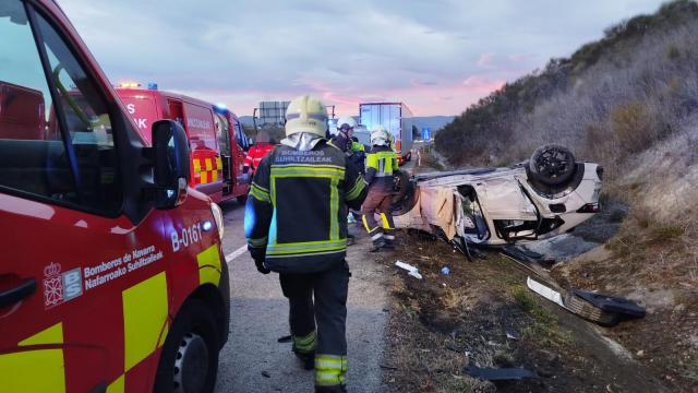 Bomberos junto al coche accidentado en la A-15 en Esquíroz. CEDIDA