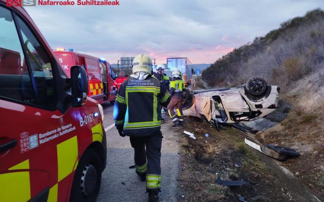 Bomberos junto al coche accidentado en la A-15 en Esquíroz. CEDIDA