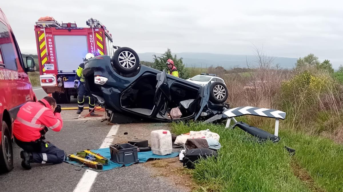 Imagen del coche volcado fuera de la carretera.