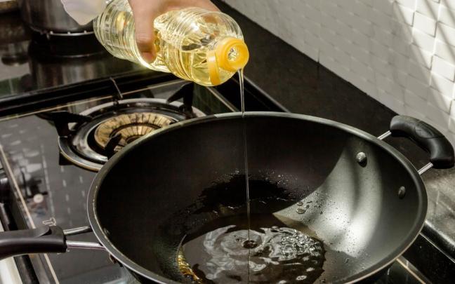 Un cocinero vierte aceite de girasol antes de cocinar.