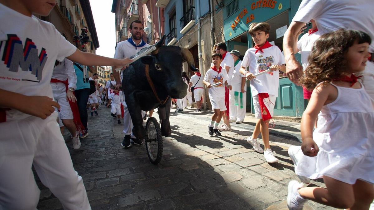 Una niña, corriendo delante de uno de los toros impulsado por un hombre