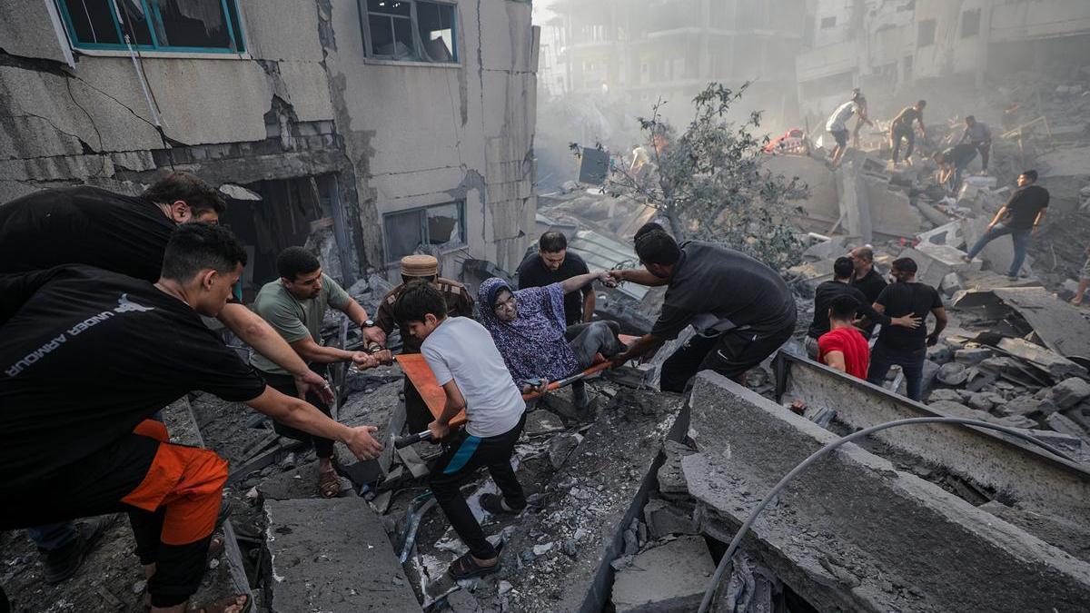 Varias personas trasladan a una mujer herida en un ataque israelí sobre Gaza.