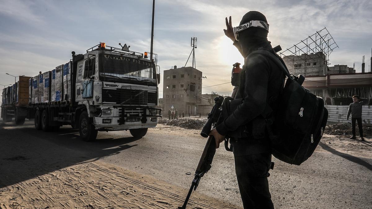 Un militar palestino saluda al conductor de un camión con ayuda humanitaria en Jan Yunis.