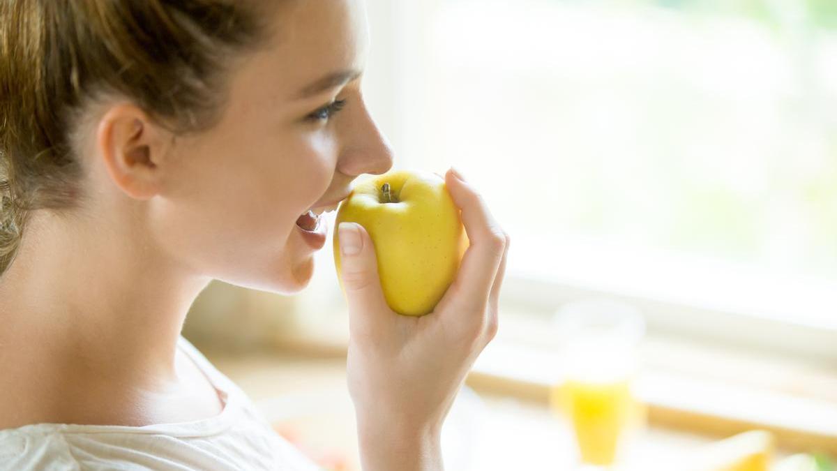 Chica joven muerde una manzana