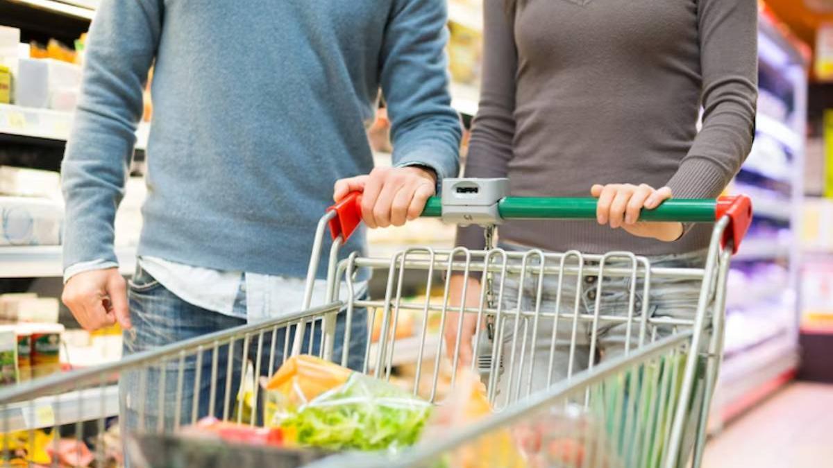 Pareja con el carro de la compra por los pasillos del supermercado