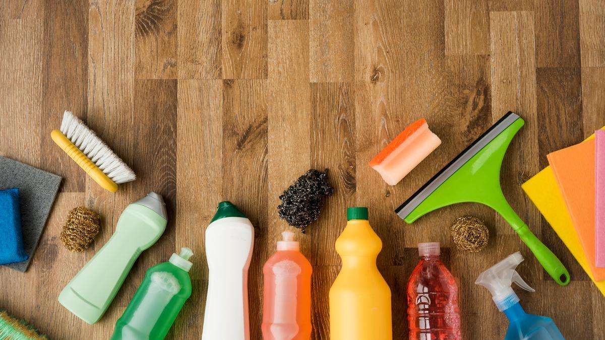 Botellas con productos de limpieza junto a estropajos, bayetas y limpiacristales.