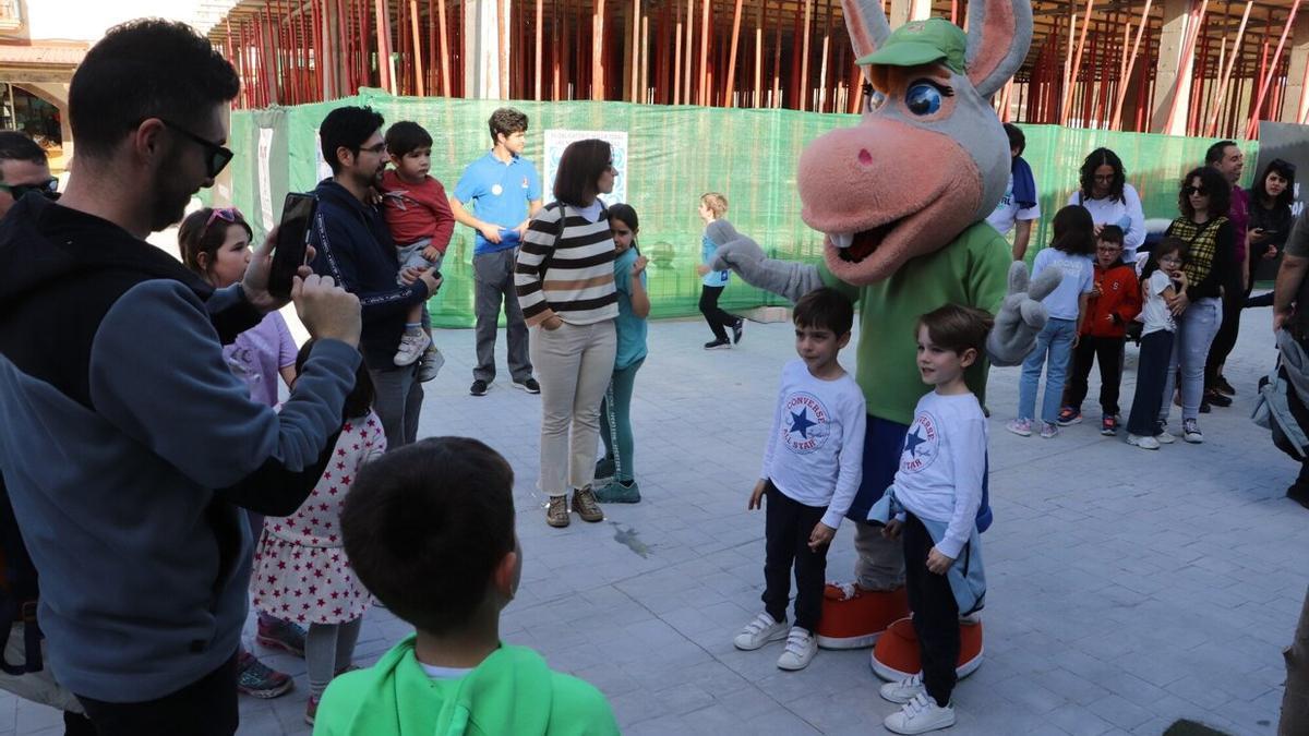 Dos niños posan con la mascota Palmira a la entrada a Sendaviva