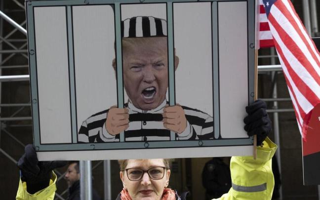 Una mujer sujeta un cartel con un montaje de Trump entre rejas.