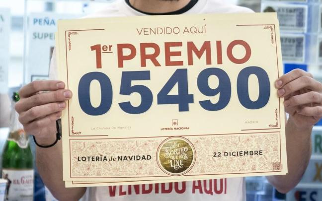 Un empleado de una de las la administraciones que vendieron el Gordo de 2022, el 05490, con un cartel con el número. Un empleado de una de las la administraciones que vendieron el Gordo de 2022, el 05490, con un cartel con el número.
