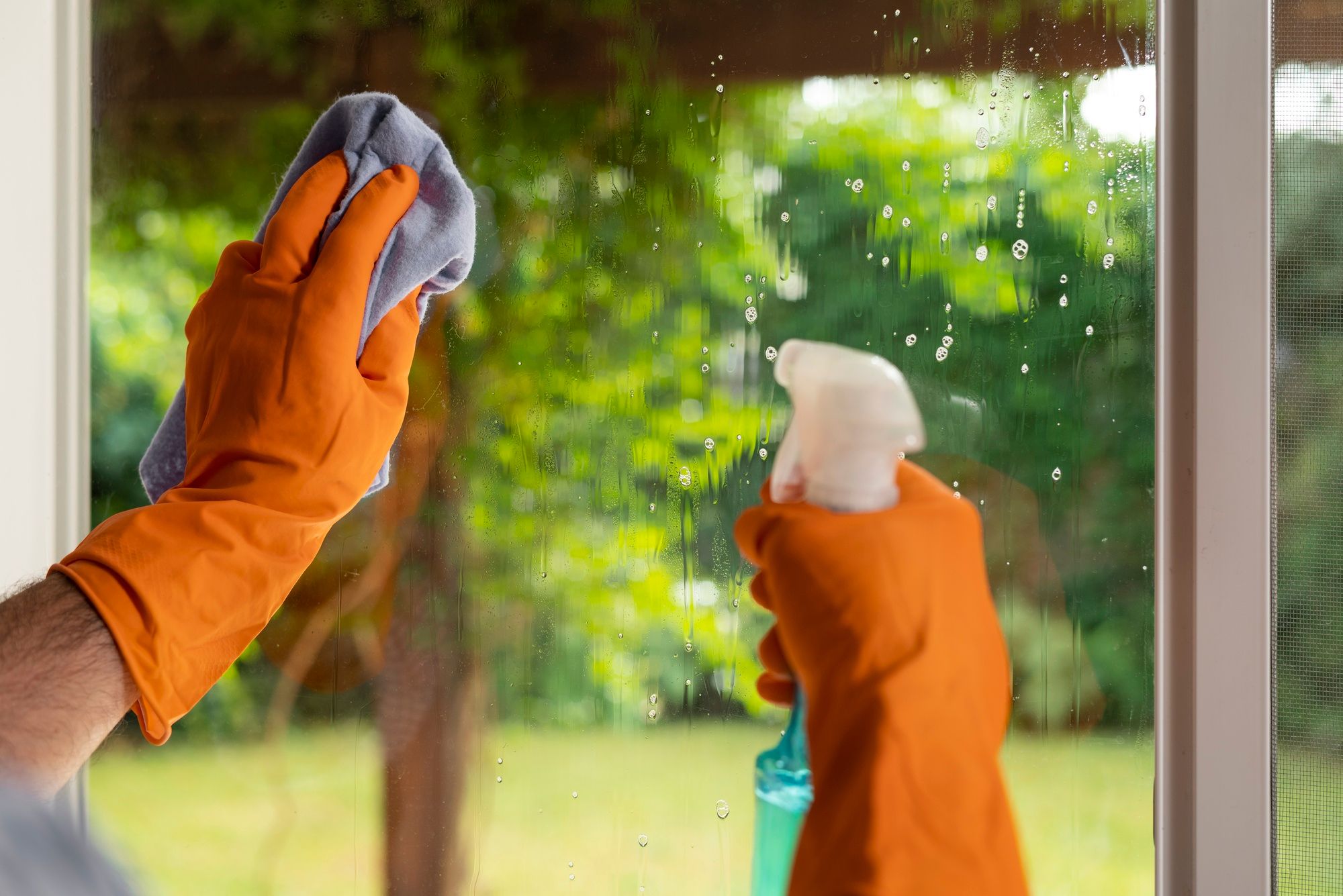 Un hombre pulveriza agua jabonosa sobre el cristal de una ventana.