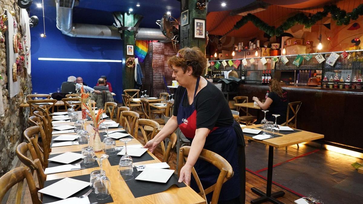 Una camarera prepara la mesa de un restaurante.