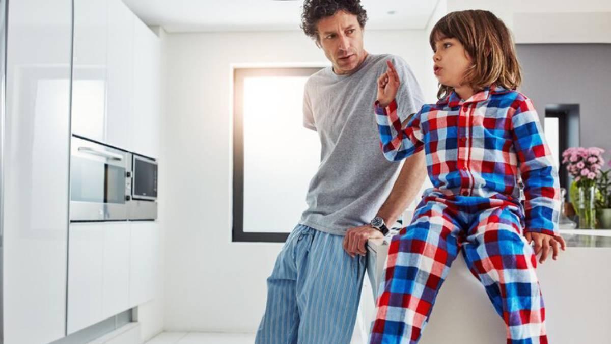 Niño junto a su padre en pijama en la cocina recién levantados.