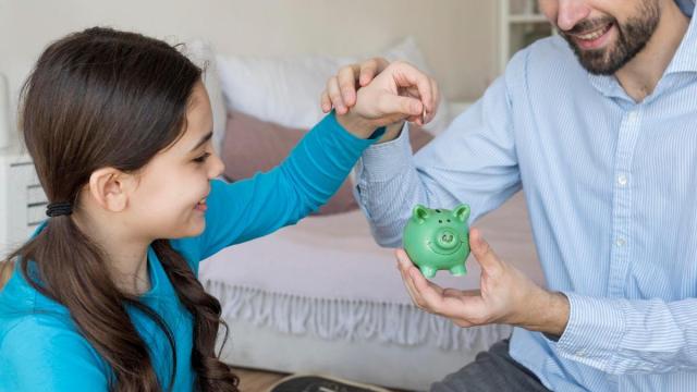 Padre e hija poniendo dinero en la hucha. Padre e hija poniendo dinero en la hucha.