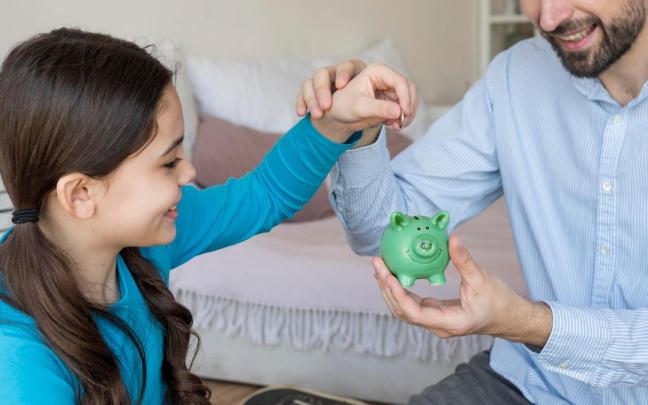 Padre e hija poniendo dinero en la hucha. Padre e hija poniendo dinero en la hucha.