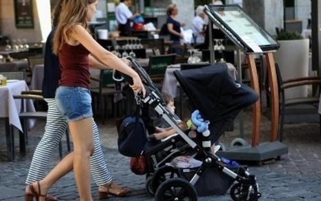 Dos jóvenes pasean con sus carritos de bebé.