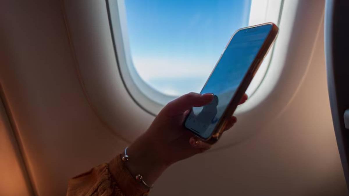 Mano de una chica utilizando su móvil en modo avión durante el vuelo