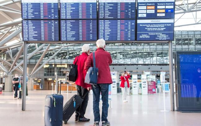 Dos hombres frente a un panel informativo en el aeropuerto de Hamburgo.