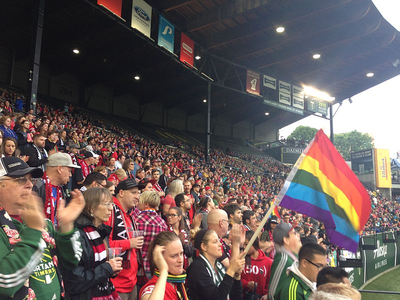 Aficionados con una bandera LGTBI en un partido de futbol