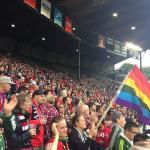 Aficionados con una bandera LGTBI en un partido de futbol