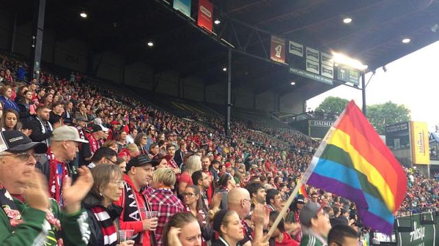 Aficionados con una bandera LGTBI en un partido de futbol