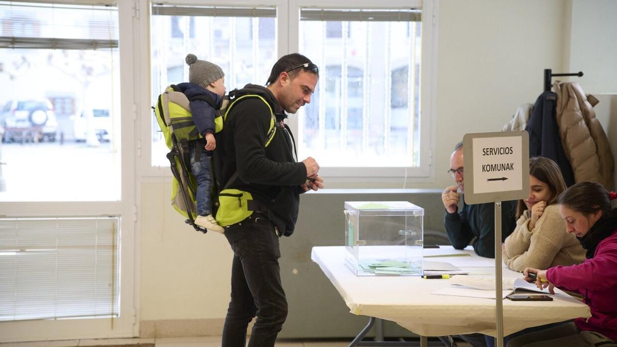 Un padre, con su hijo a cuestas en una mochila, vota en el concejo de Arre. Foto: Iñaki Porto