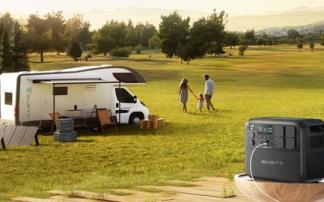 Autocaravana estacionada en un campo junto a una familia y una estación de energía portáti