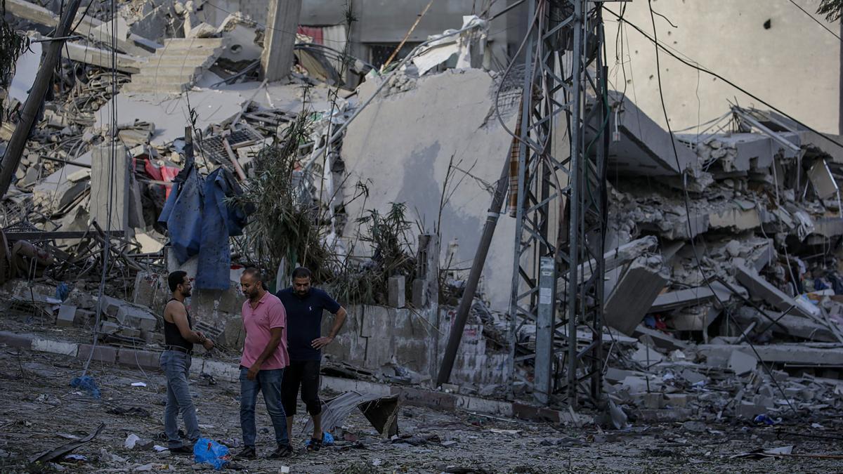 Tres palestinos junto a un edificio derruido por las bombas de Israel.