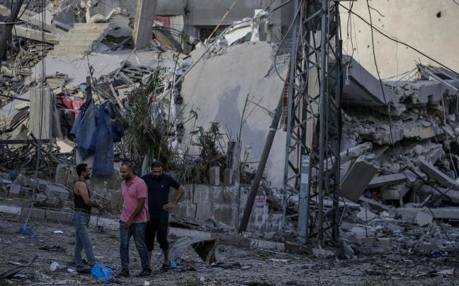 Tres palestinos junto a un edificio derruido por las bombas de Israel.