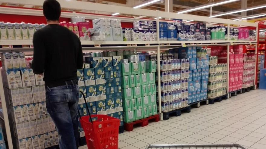 Un hombre, decidiendo qué leche comprar en un supermercado.