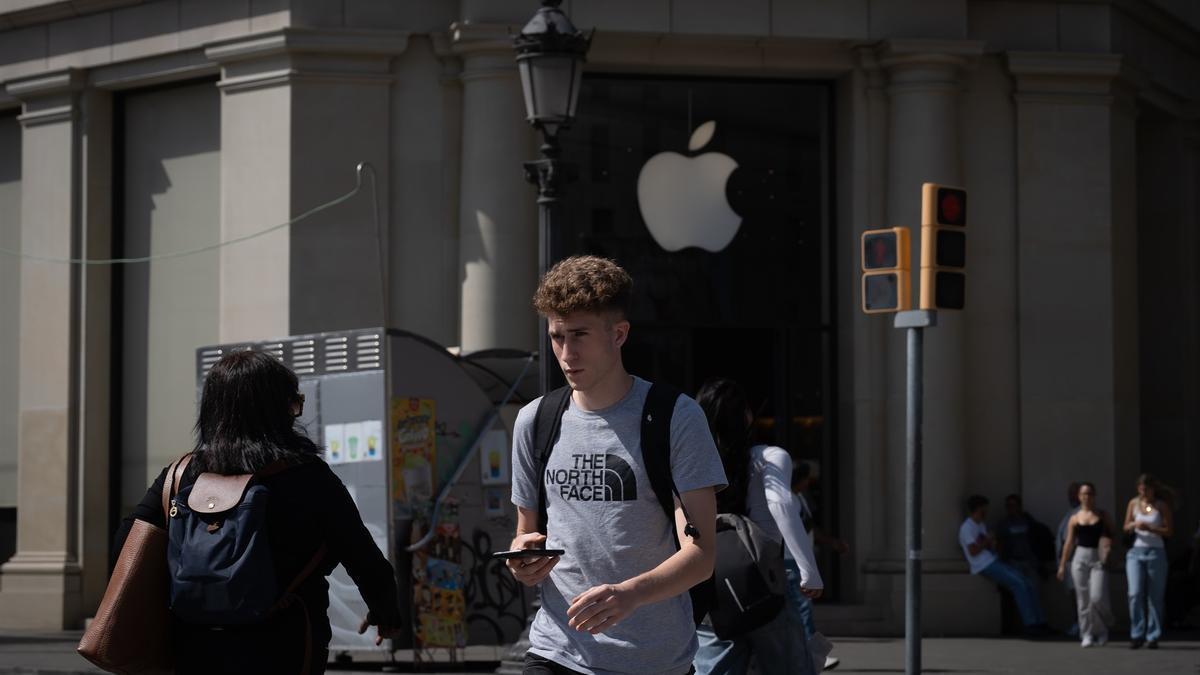 Varias personas caminan frente a una tienda de Apple.