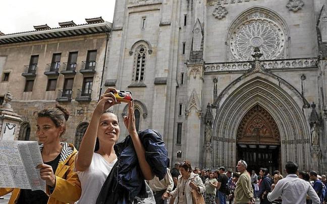 Dos jóvenes se hacen un selfi y consultan un mapa turístico junto a la catedral de Santiago, durante una visita a Euskadi. | FOTO: PABLO VIÑAS