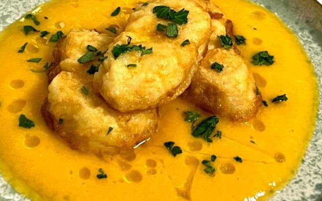 Medallones de merluza sobre una crema de calabaza y langostinos.