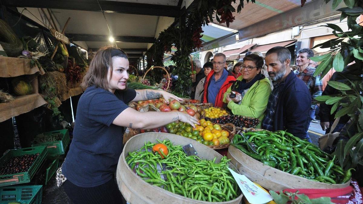 Una mujer atiende a los clientes en un puesto de frutas y hortalizas en la feria del Último Lunes de Octubre, en Gernika.