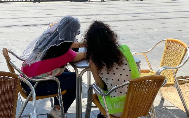 Dos jóvenes disfrutan de una despedida de soltera, en la terraza de un bar de la calle San Fernando de Sevilla.
