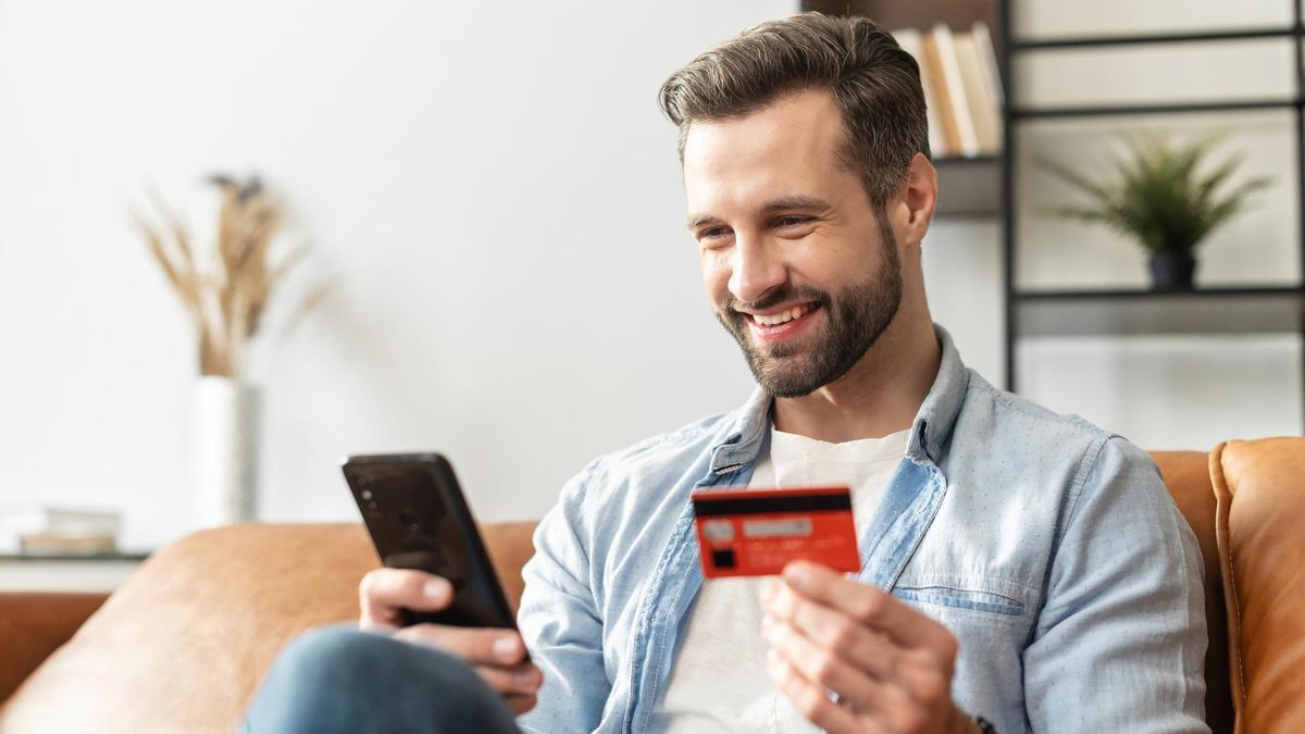 Un hombre hace una compra online con tarjeta a través del teléfono móvil.