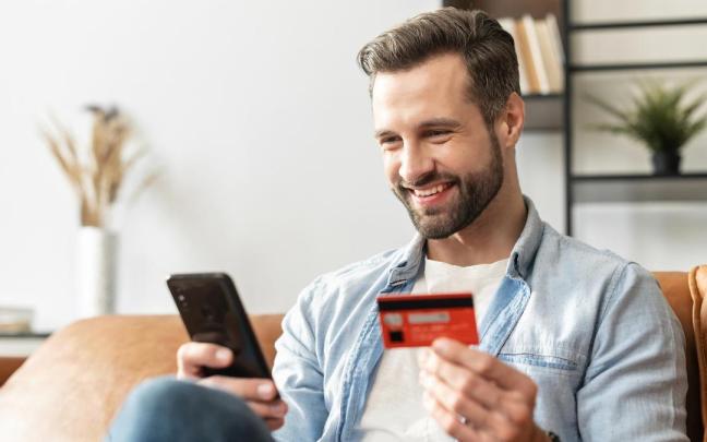 Un hombre hace una compra online con tarjeta a través del teléfono móvil.