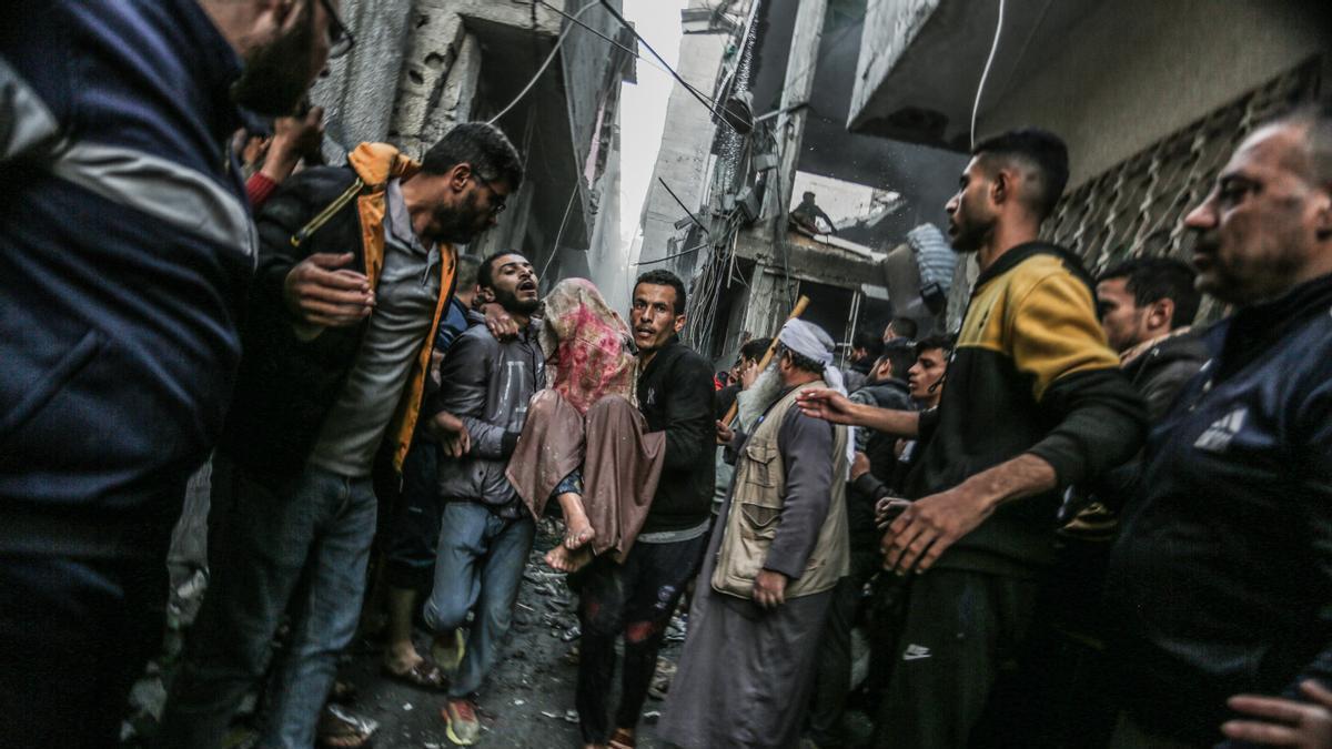 Dos palestinos trasladan a una víctima de un bombardeo israelí en Rafah.