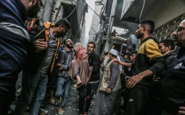 Dos palestinos trasladan a una víctima de un bombardeo israelí en Rafah.