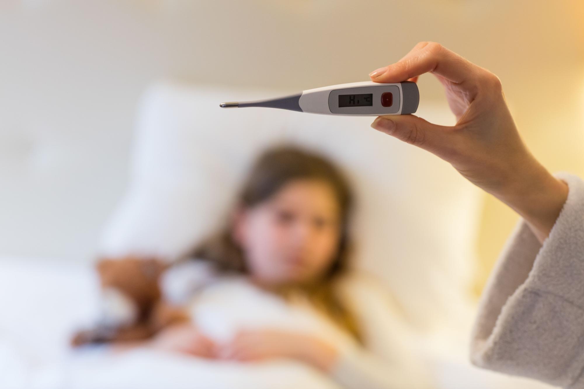 Madre comprueba si su hija tiene fiebre con un termómetro infantil.