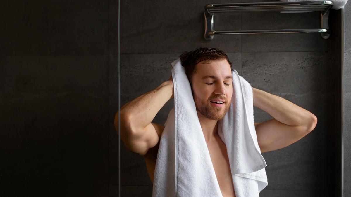 Un hombre se seca el pelo con una toalla después de la ducha.