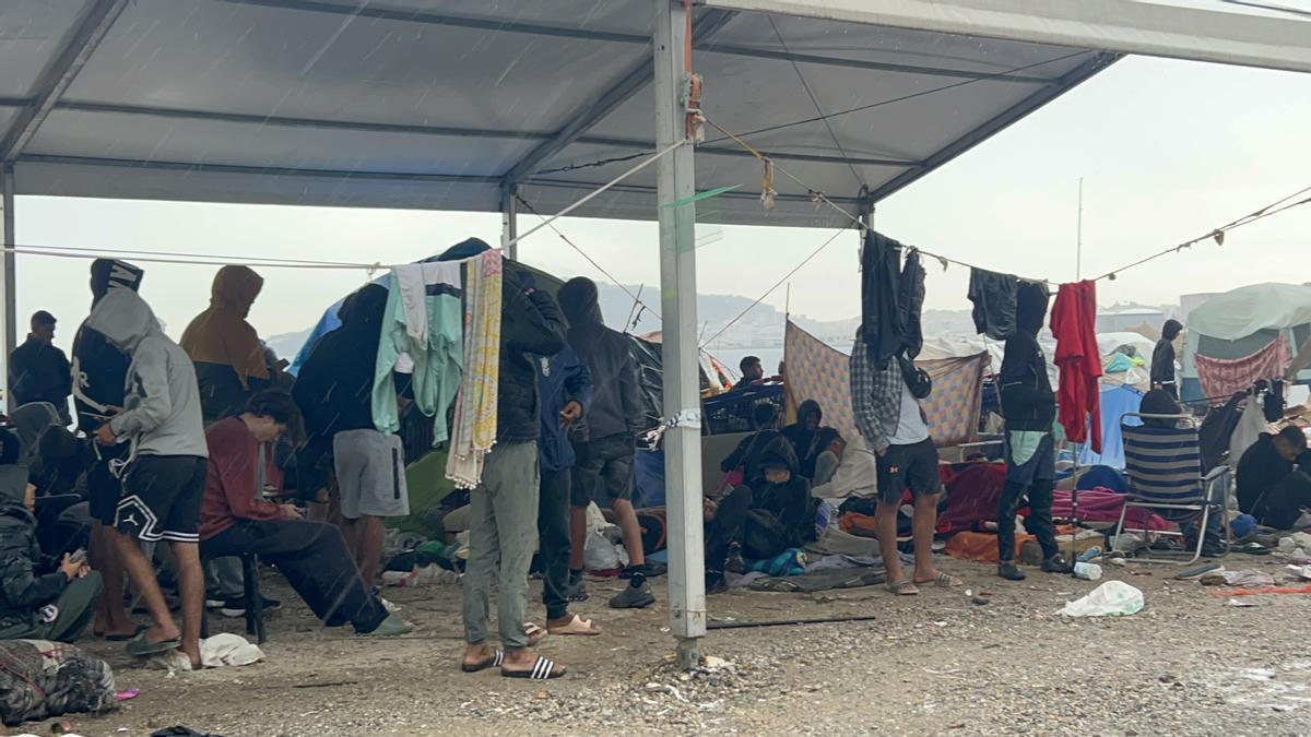 Varios migrantes esperan a ser trasladados en la explanada del Guano.
